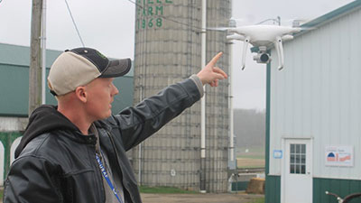 William Thiele points at airborne drone on his farm as part of Remake Learning Days.